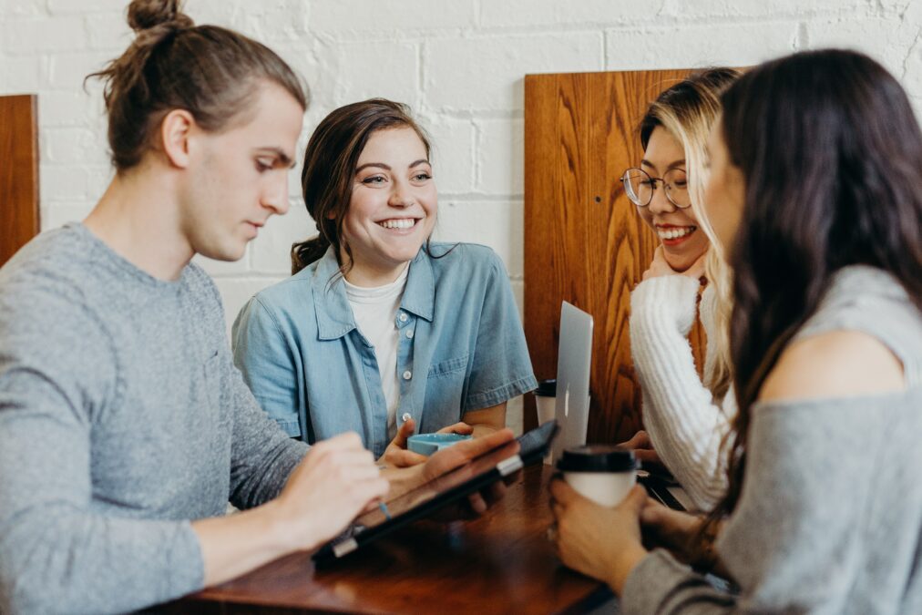 A group of people around a table smiling and looking at devices