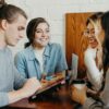 A group of people around a table smiling and looking at devices